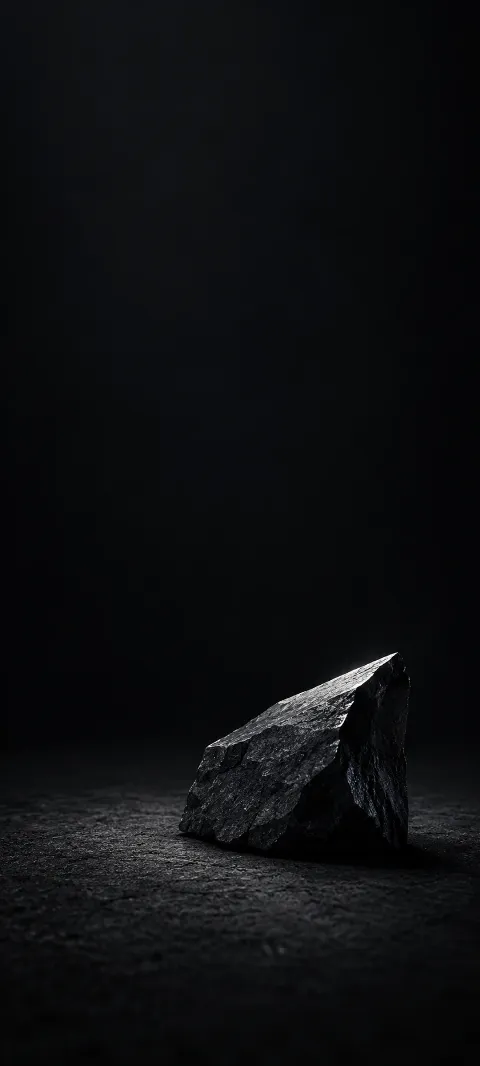 Small angular dark stone with a narrow silver highlight on a black surface.