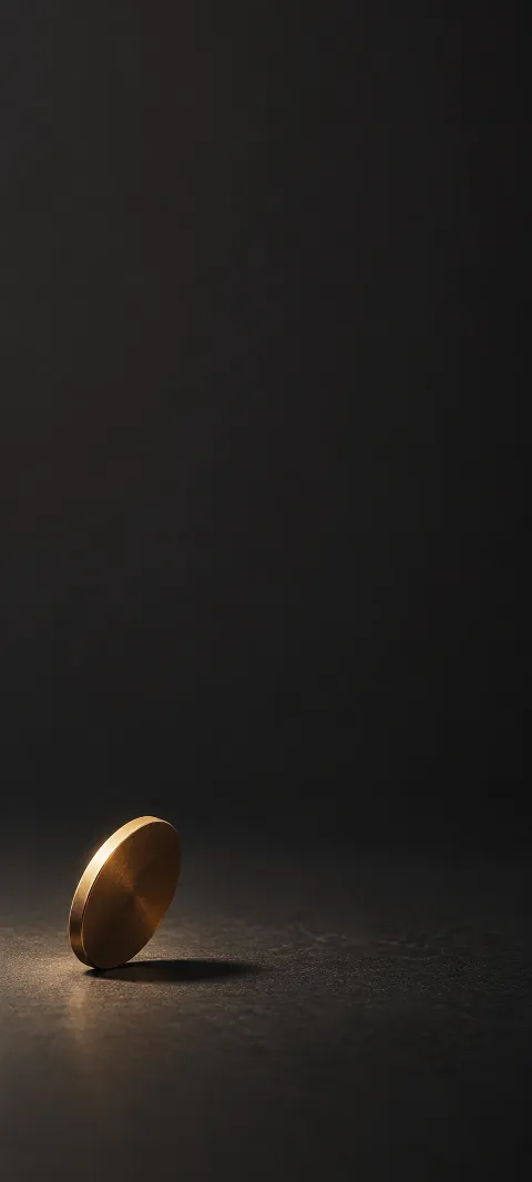 Small plain bronze disk tilted on a dark charcoal studio surface.