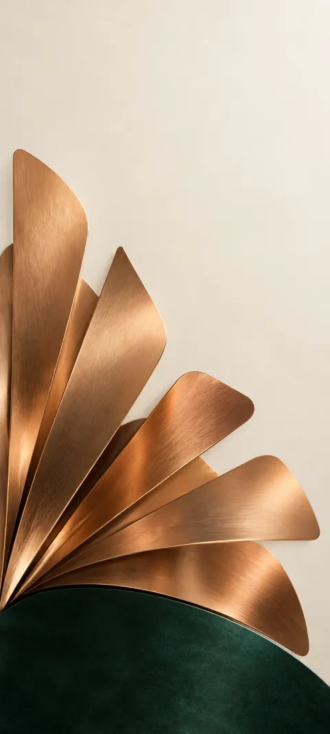 Brushed copper blades fanned above a dark emerald plate on ivory.