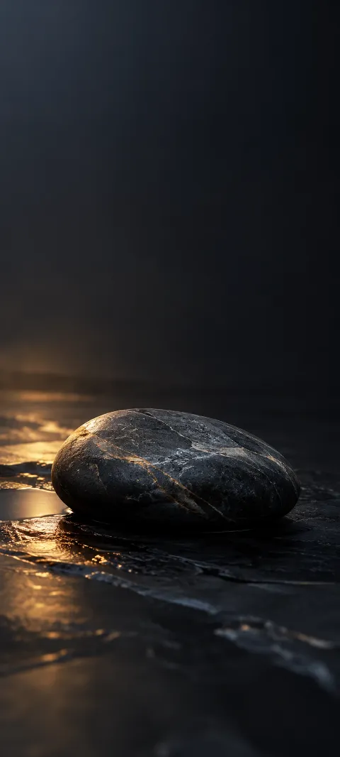 A dark slate pebble rests on a nearly black plane.