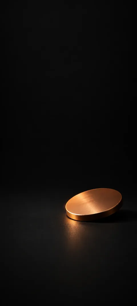 Angled copper disc with a warm rim highlight on a black surface.