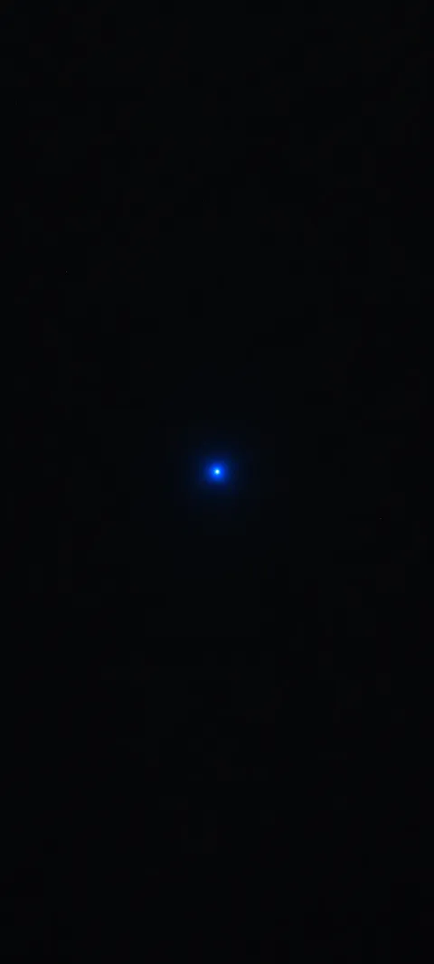 A single small blue point with a faint halo centered on black.