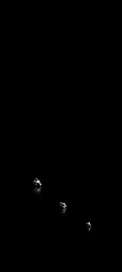 Three small irregular reflective silver fragments on a black background.