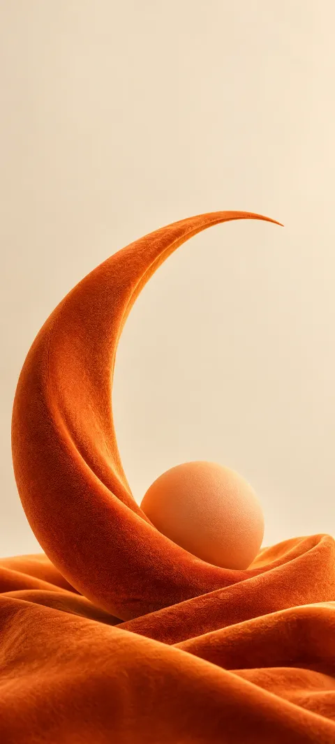 Orange velvet crescent and apricot sphere on folded fabric against warm ivory.