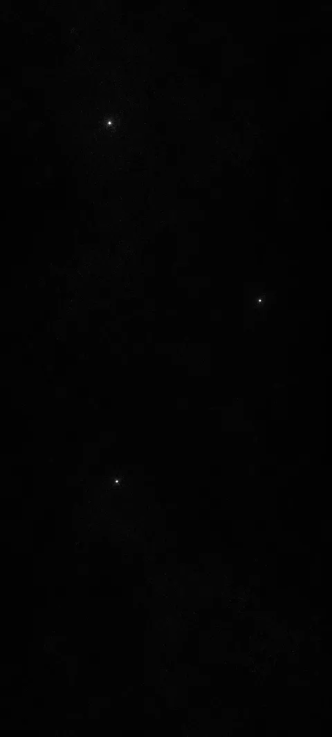 Three tiny silver specks punctuate a deep black field.