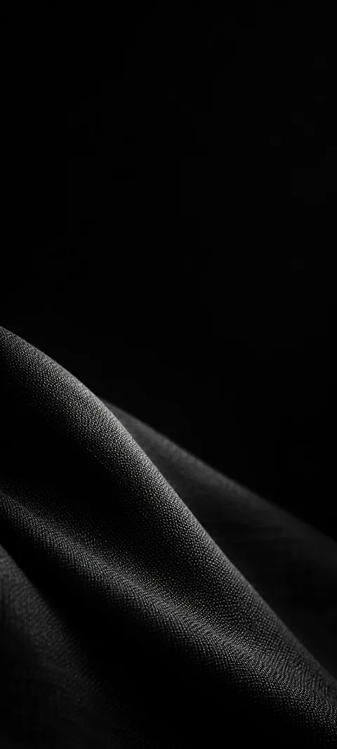 Diagonal charcoal fabric fold with a softly highlighted woven texture.