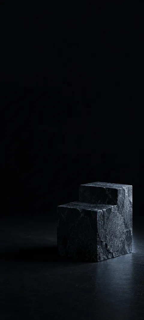 Stepped dark stone block with cool side lighting on a black studio floor.