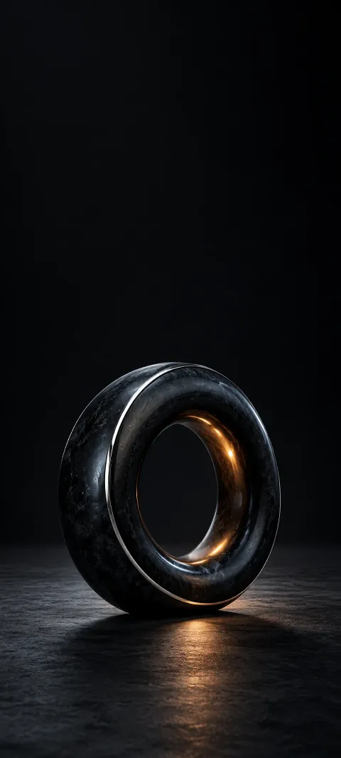 Dark obsidian ring with silver edging and warm amber reflections on charcoal.