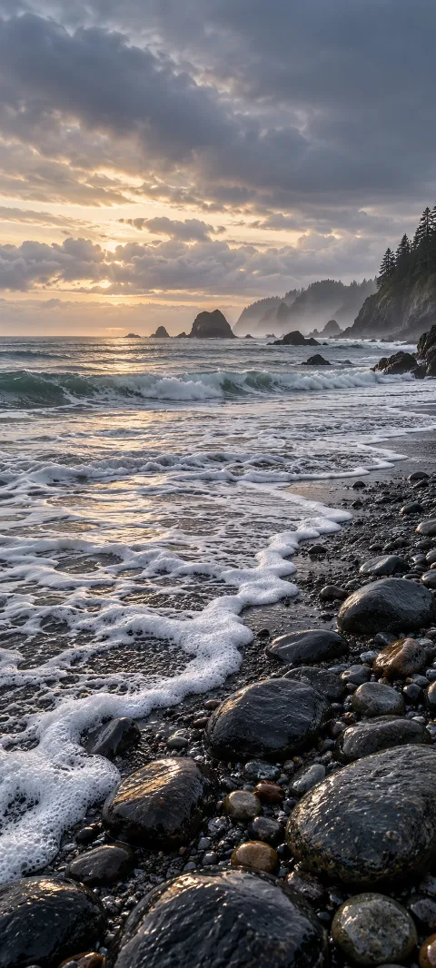 Seafoam curls along a dark pebble shoreline.
