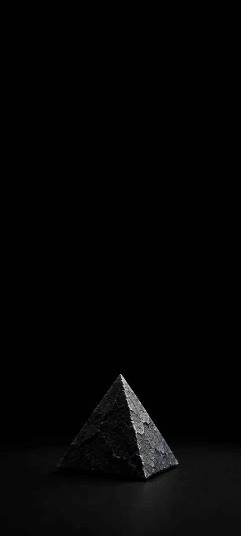 A rough charcoal pyramid low on a black surface.