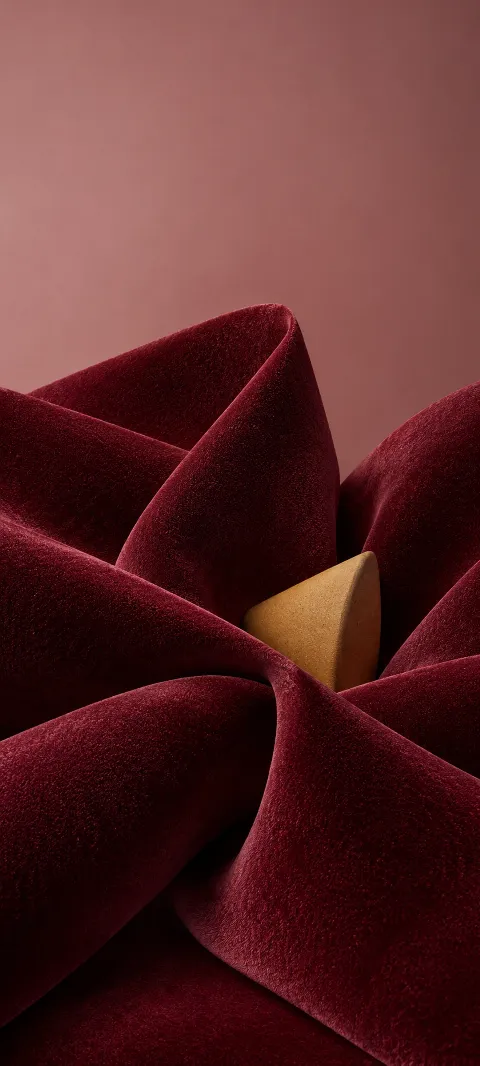 Burgundy velvet folds surrounding an ochre ceramic wedge on dusty rose.