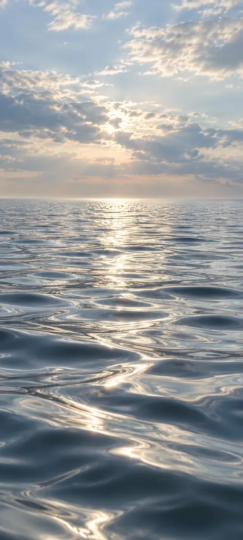 Silver ripples cross a quiet lake beneath pale clouds.