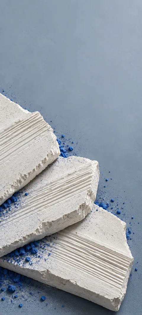 Grooved ivory chalk slabs with cobalt powder on a gray-blue background.