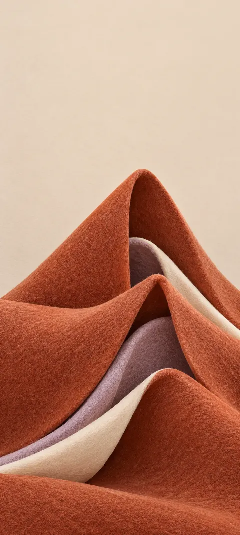 Terracotta felt folds with lavender and ivory layers on a pale sand field.