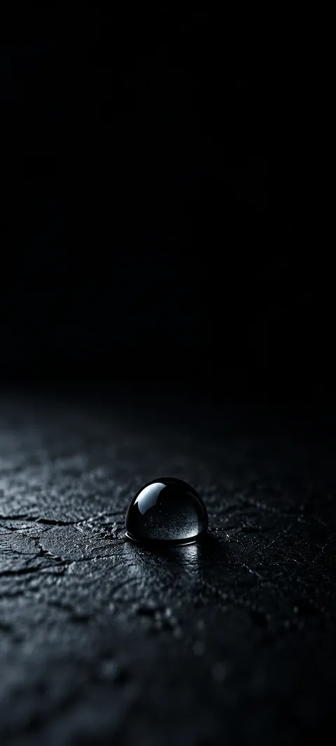 A dark droplet catches a tiny cool reflection.