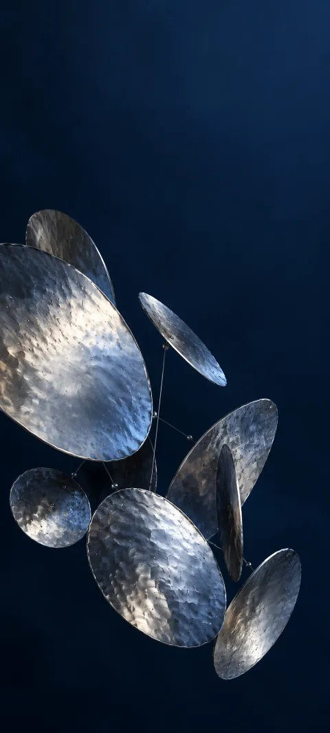 Hammered silver discs suspended at different tilts against navy blue.