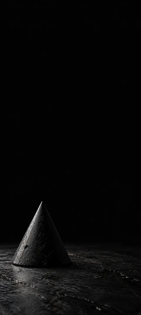 Small dark stone cone with mineral pitting and a narrow silver edge light.