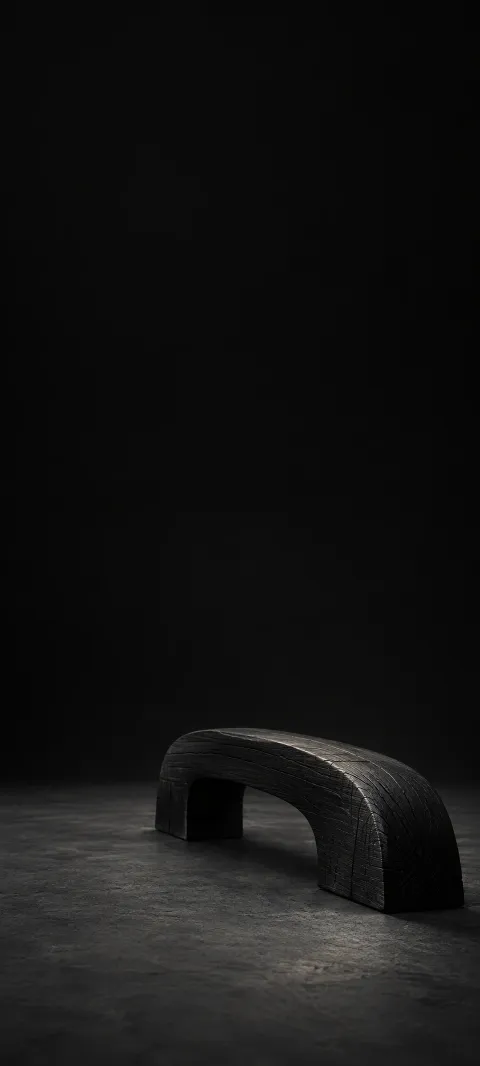 Small dark wooden arch with visible charred grain on a charcoal floor.